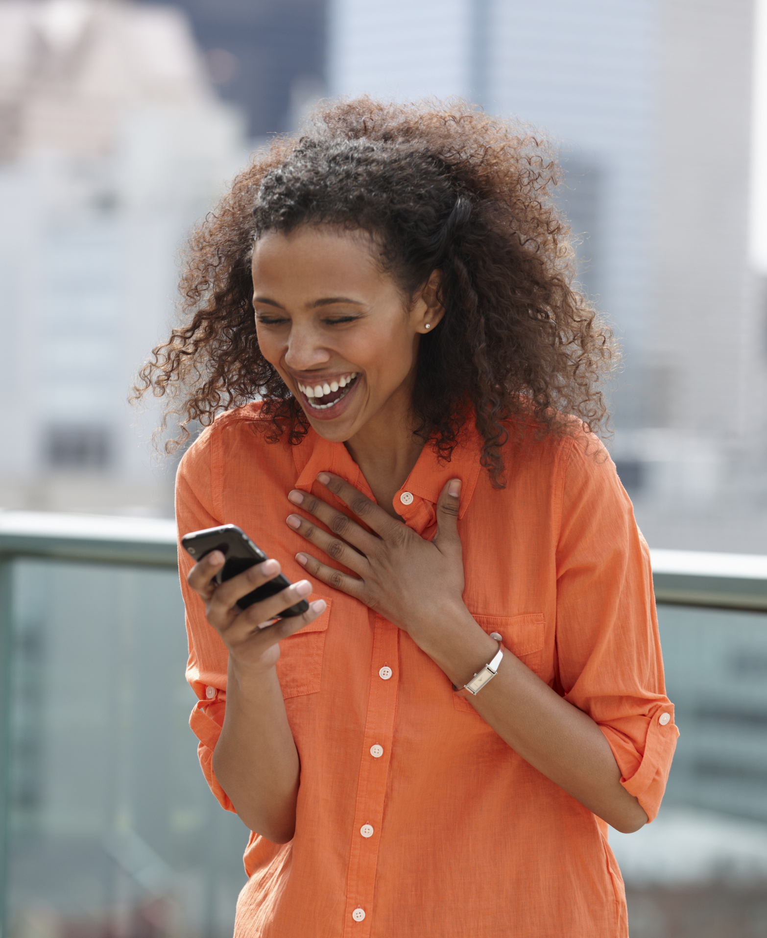 Laughing Black woman text messaging on cell phone